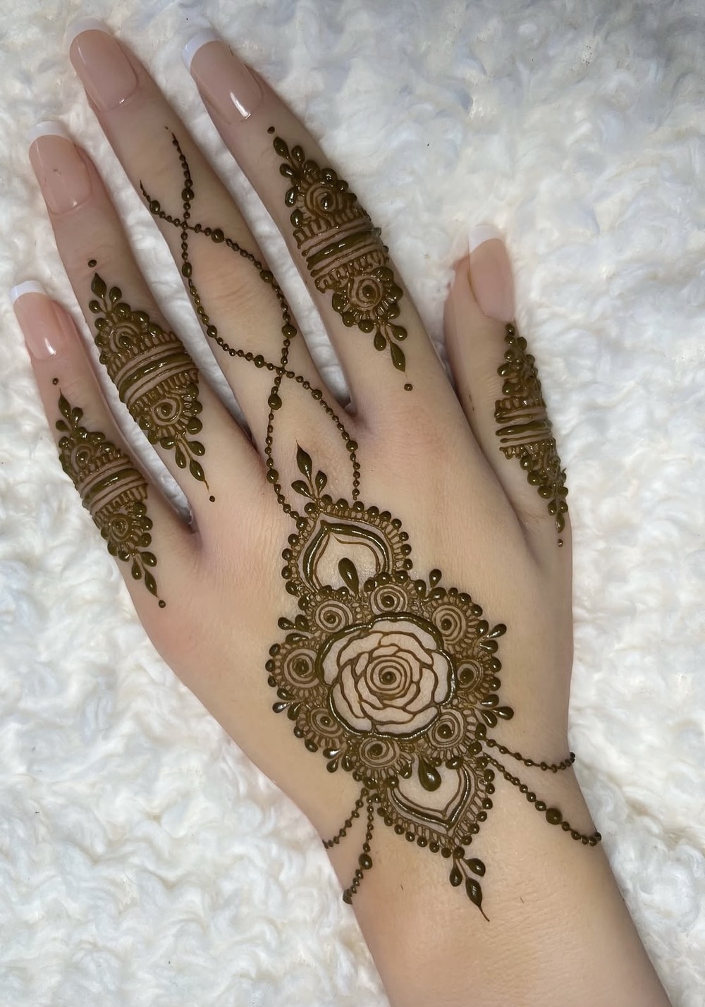 Rose-centered back-of-hand mehndi with matching finger and bracelet henna designs