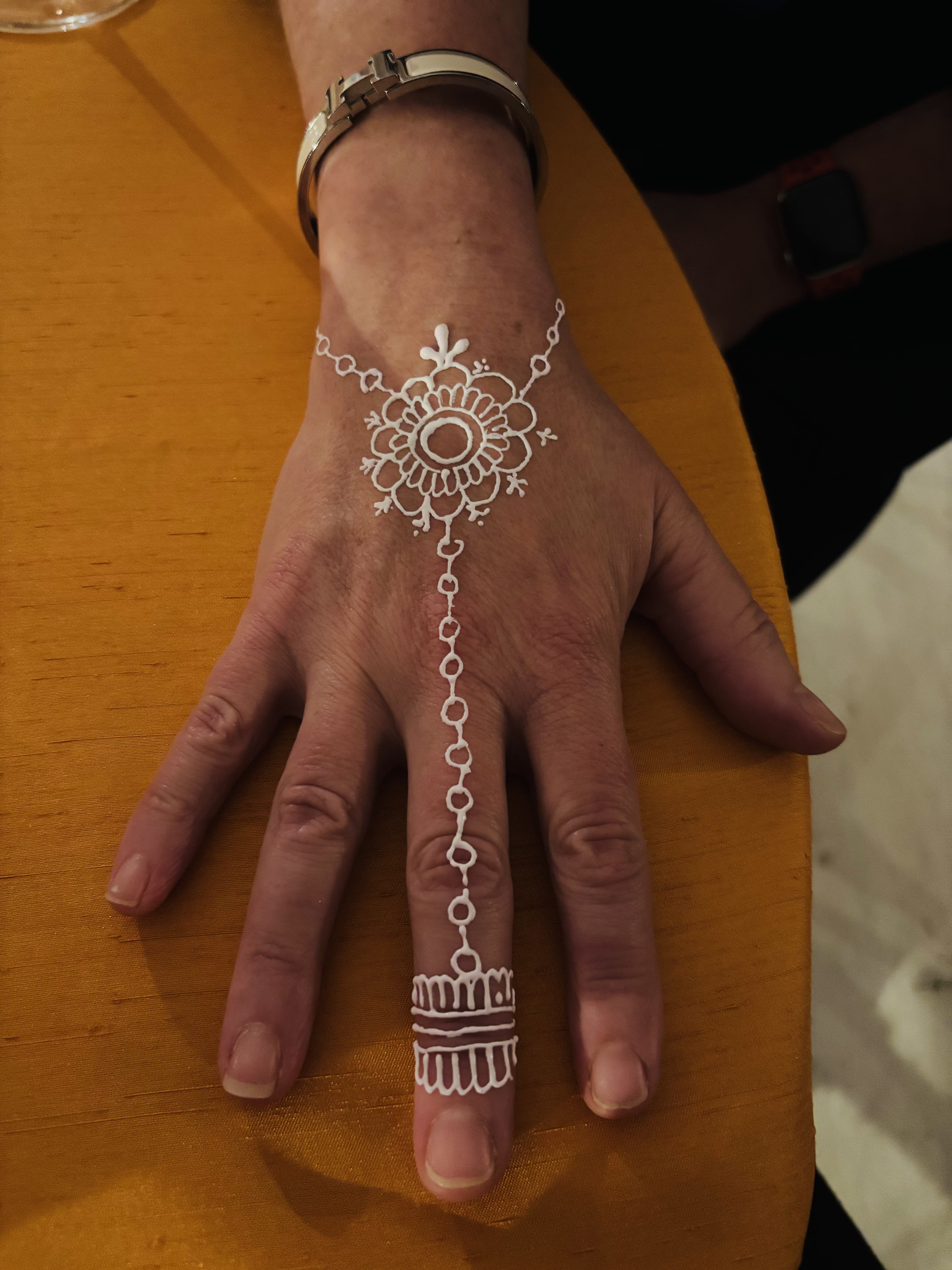 White henna vine and floral bracelet design on a hand