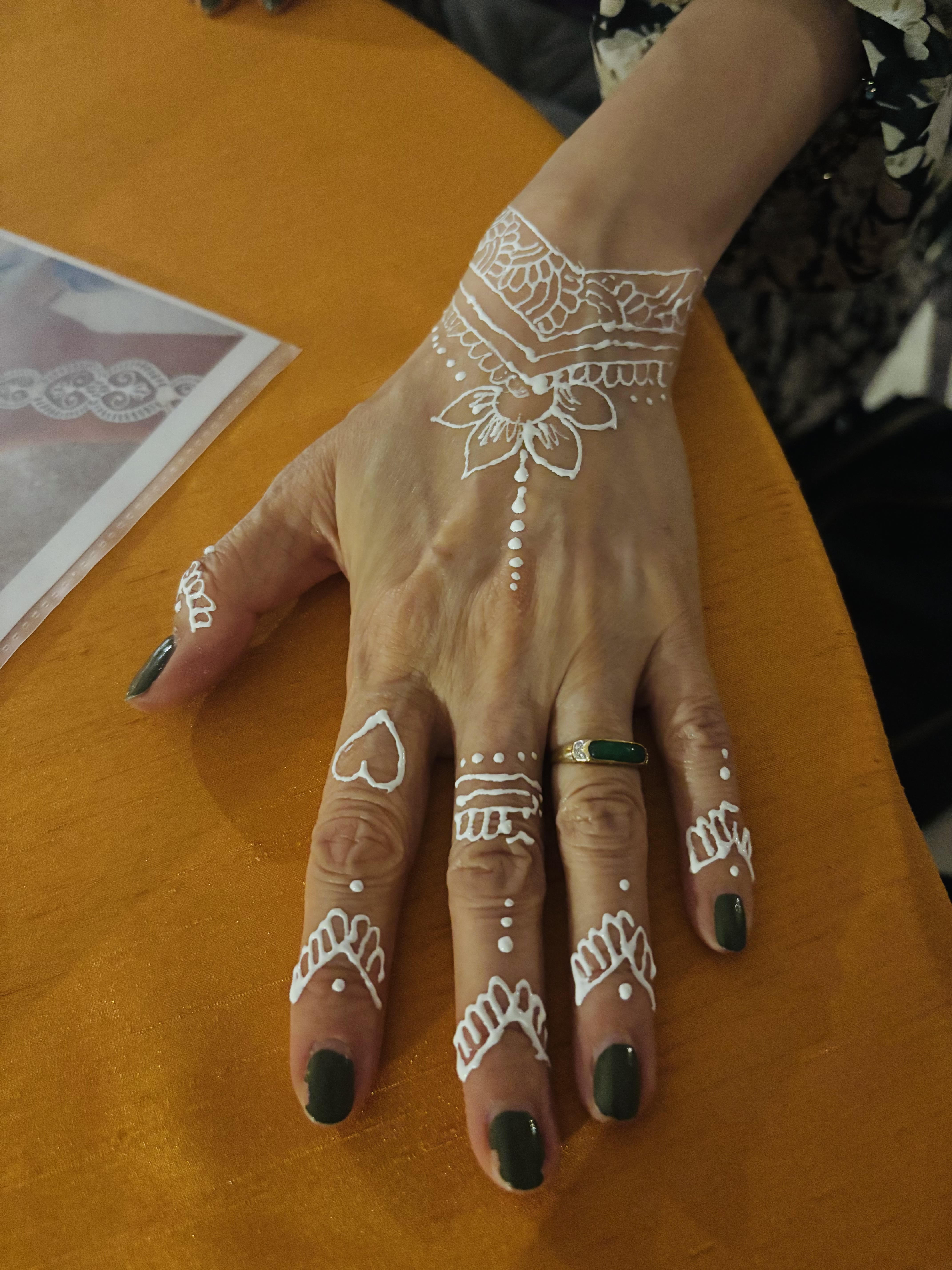 White henna lotus wristband design on a hand